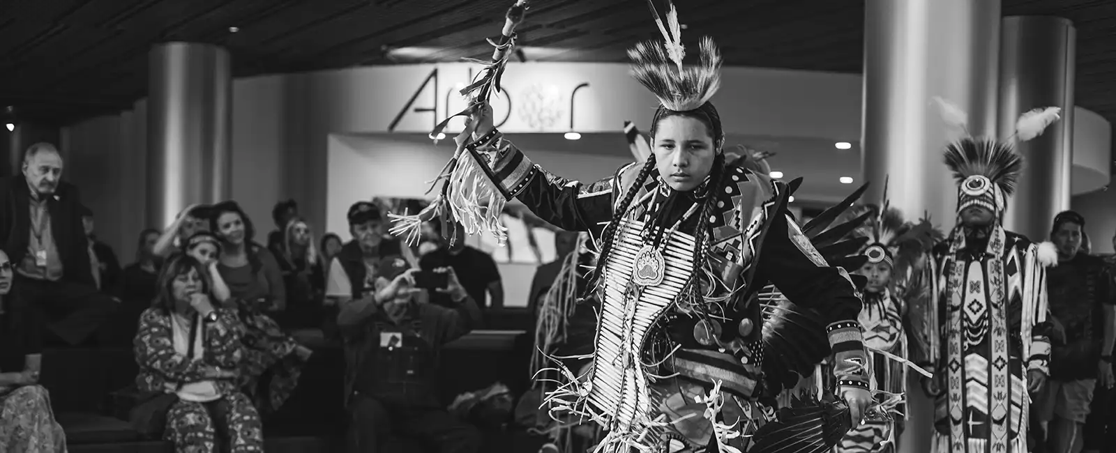 black and white photo of young native american dancing in tribal clothing